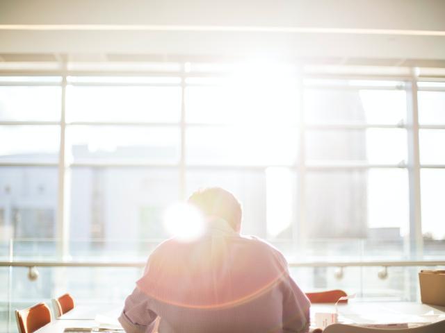 A person sitting in front of a window with sun shining through